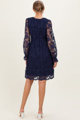 woman wearing a navy blue lace maternity dress with long sleeves and a fitted bodice, showing a flowing skirt