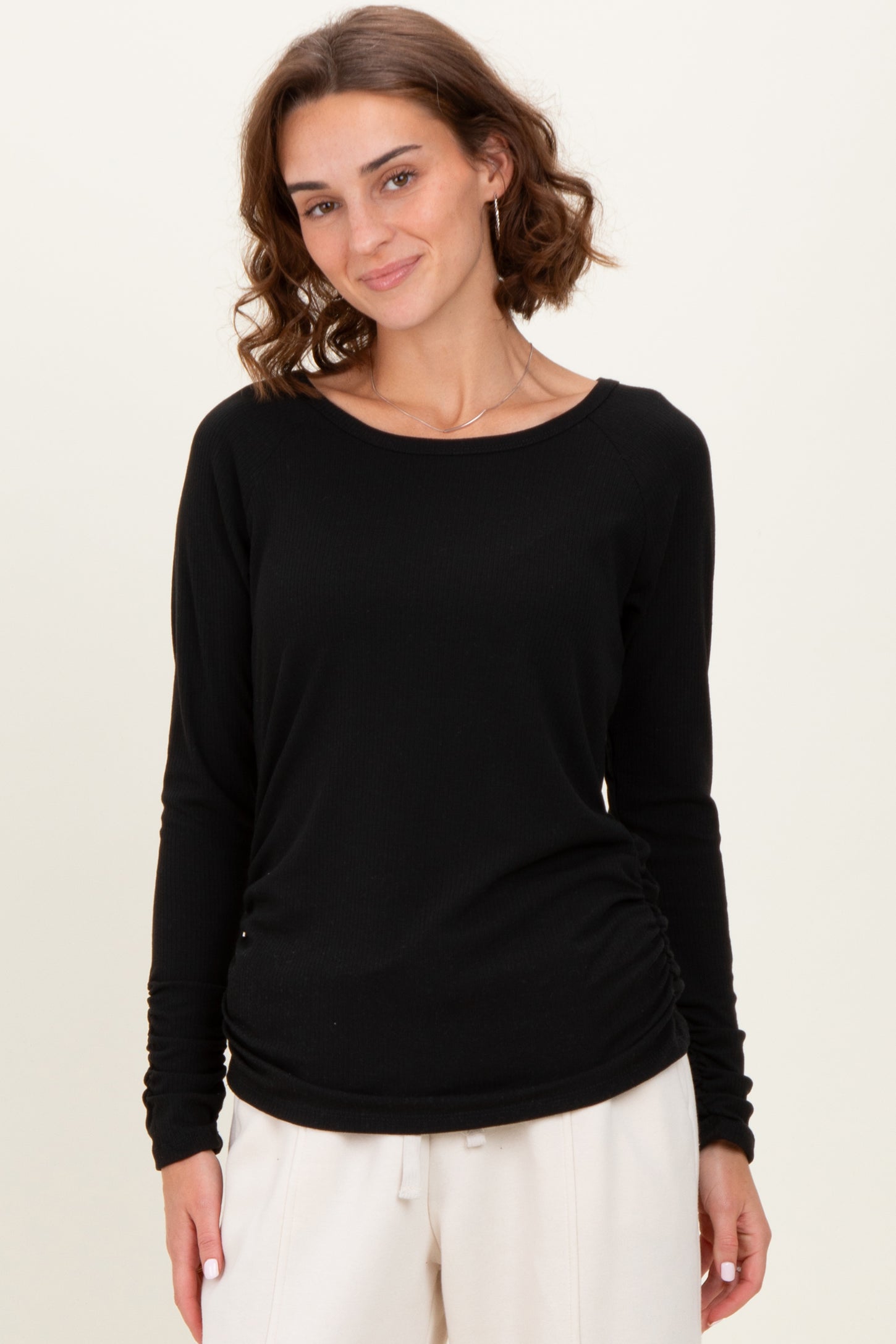 woman wearing a black long sleeve ribbed top with a relaxed fit and gathered side details