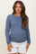 woman wearing a blue long sleeve maternity top with ruched sides and holding her baby bump