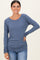 woman wearing a blue long sleeve ribbed top with ruched side details and smiling