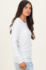 woman wearing a white long sleeve ribbed top with gathered side details and styled with light wash jeans
