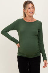 woman wearing a fitted dark green long sleeve maternity top and showing her baby bump