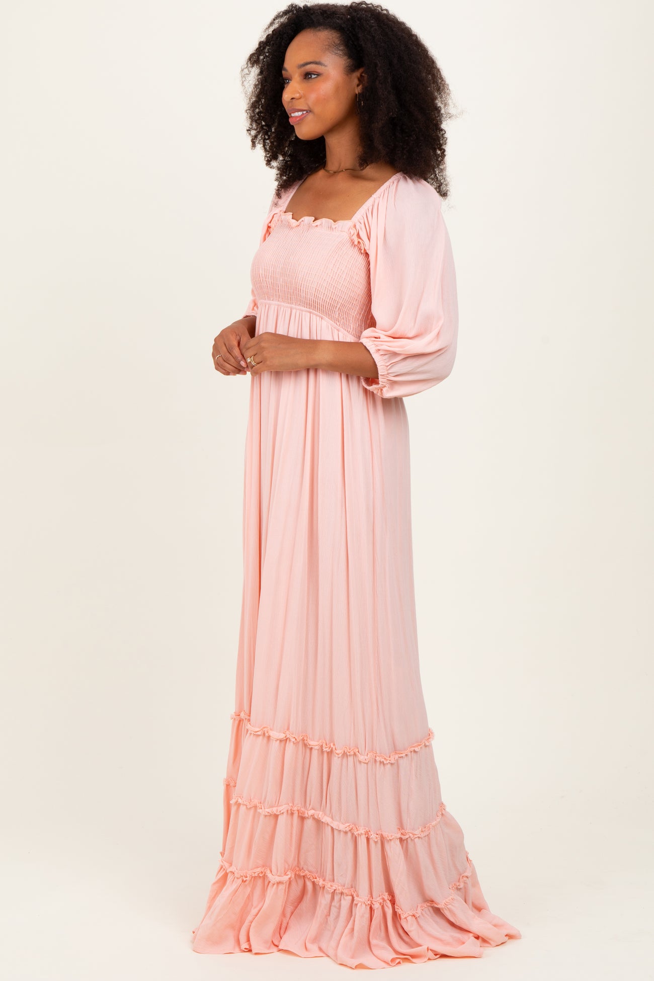 woman wearing a soft pink long maxi dress with puff sleeves and tiered ruffle details