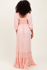 woman wearing a pastel pink maxi dress with smocked bodice and ruffled hem, viewed from the back