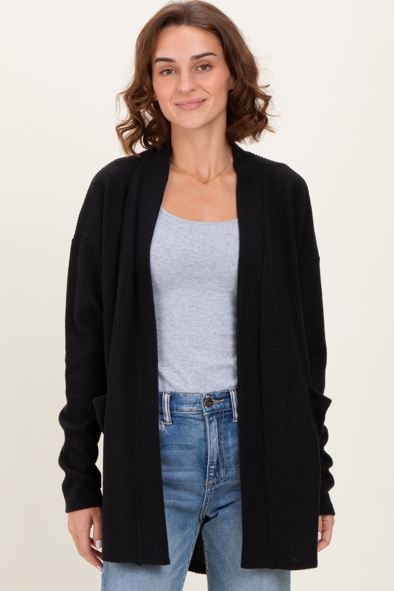 woman wearing a black ribbed open-front cardigan over a gray t-shirt and blue jeans