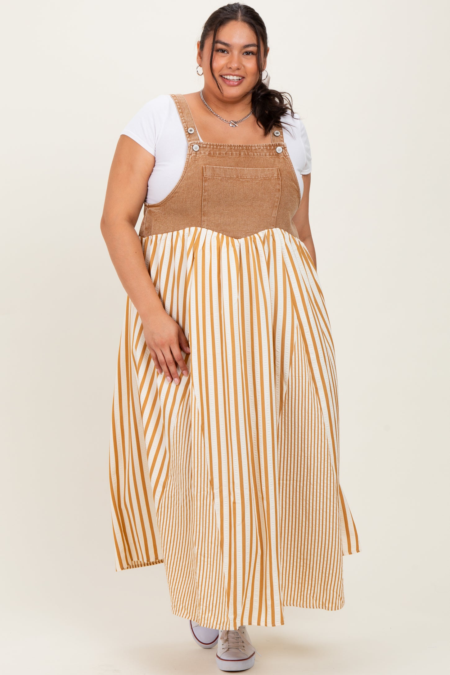 woman wearing a beige and white striped plus-size maxi dress with a corduroy top and a loose, flowing skirt