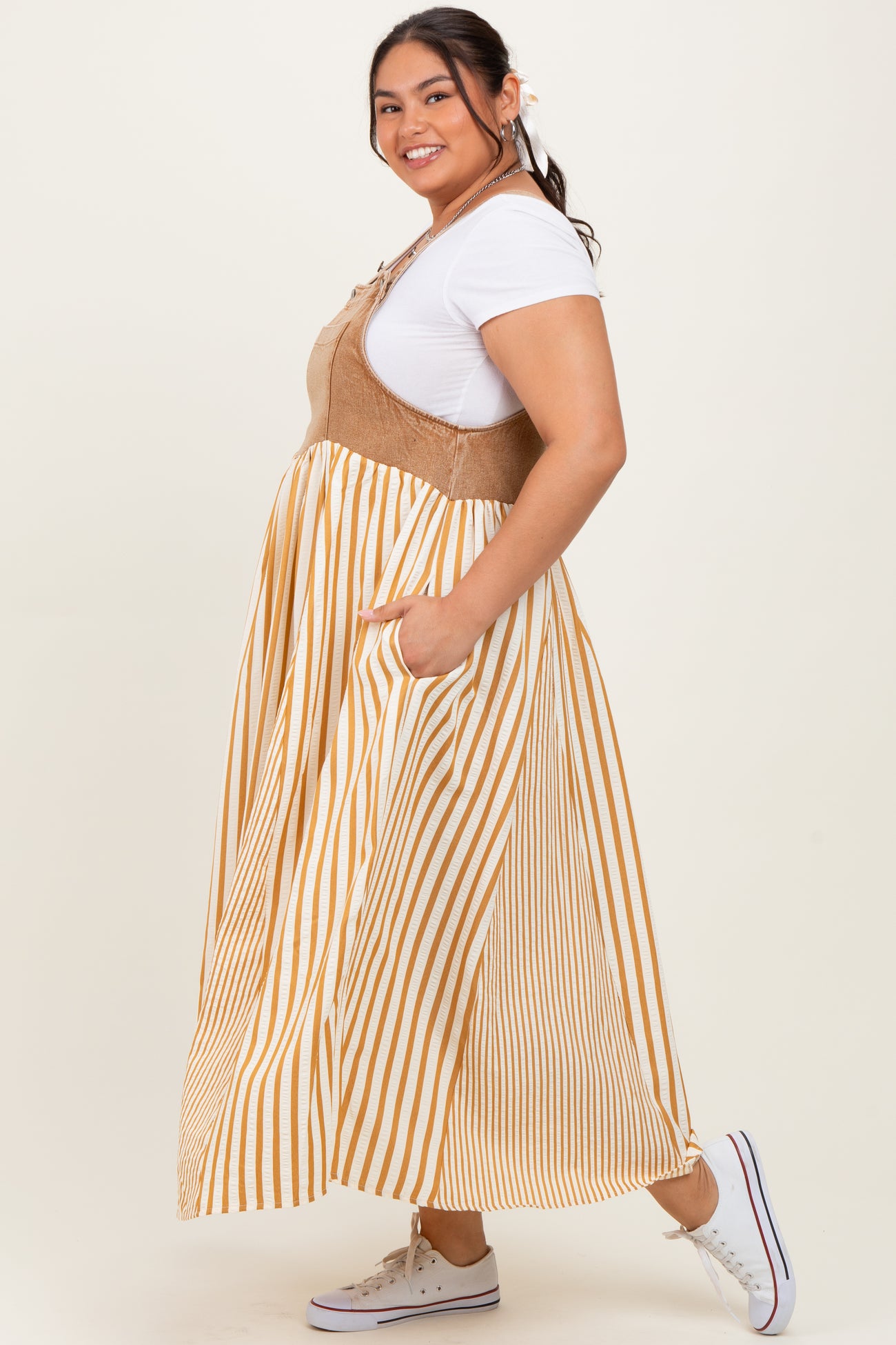woman wearing a beige and yellow striped plus size maxi dress with a tie front and pockets