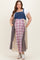 woman wearing a denim maternity plus overall dress with plaid pattern, side pockets, and a baby bump visible