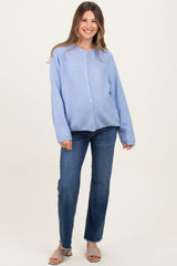 woman wearing a light blue button-up maternity sweater with loose fit and smiling at the camera