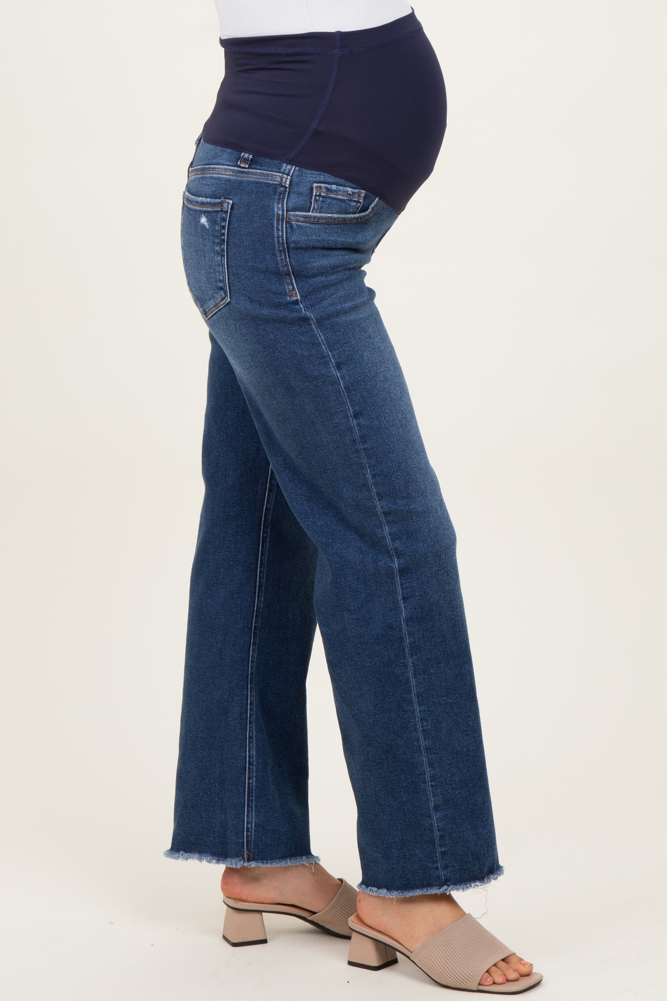 woman wearing dark blue maternity jeans with a stretchy waistband and a frayed hem, showing her baby bump