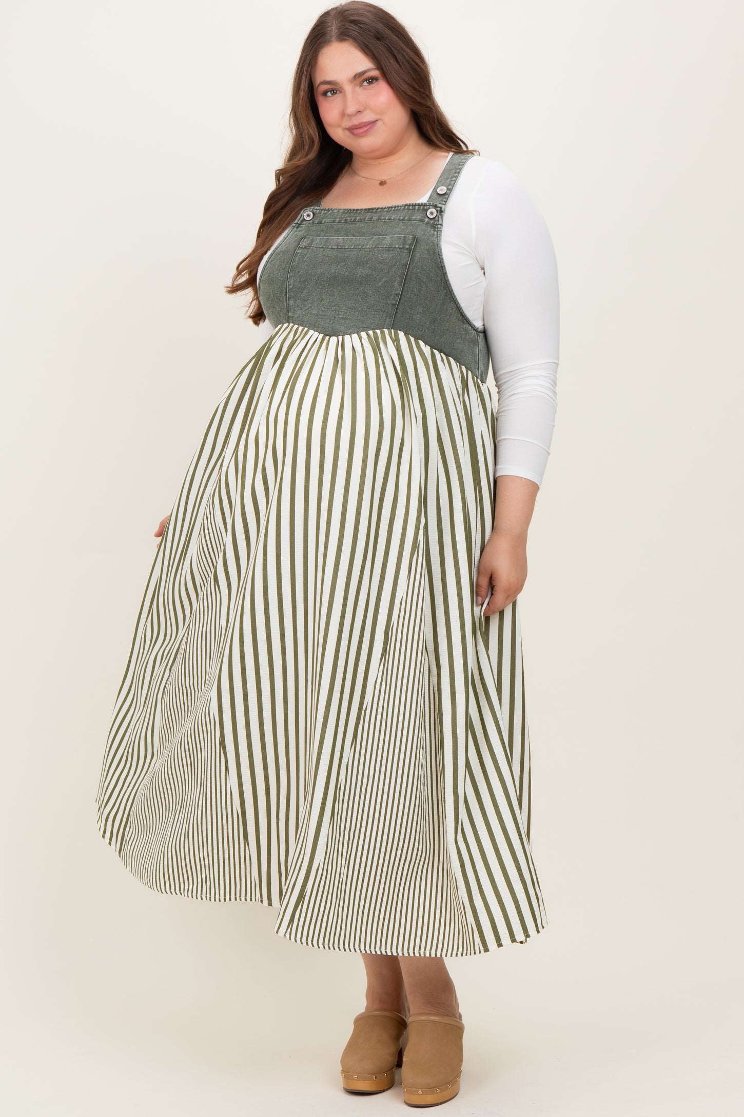woman wearing a green and white striped maternity plus dress with a fitted top and flowy skirt, showing her baby bump