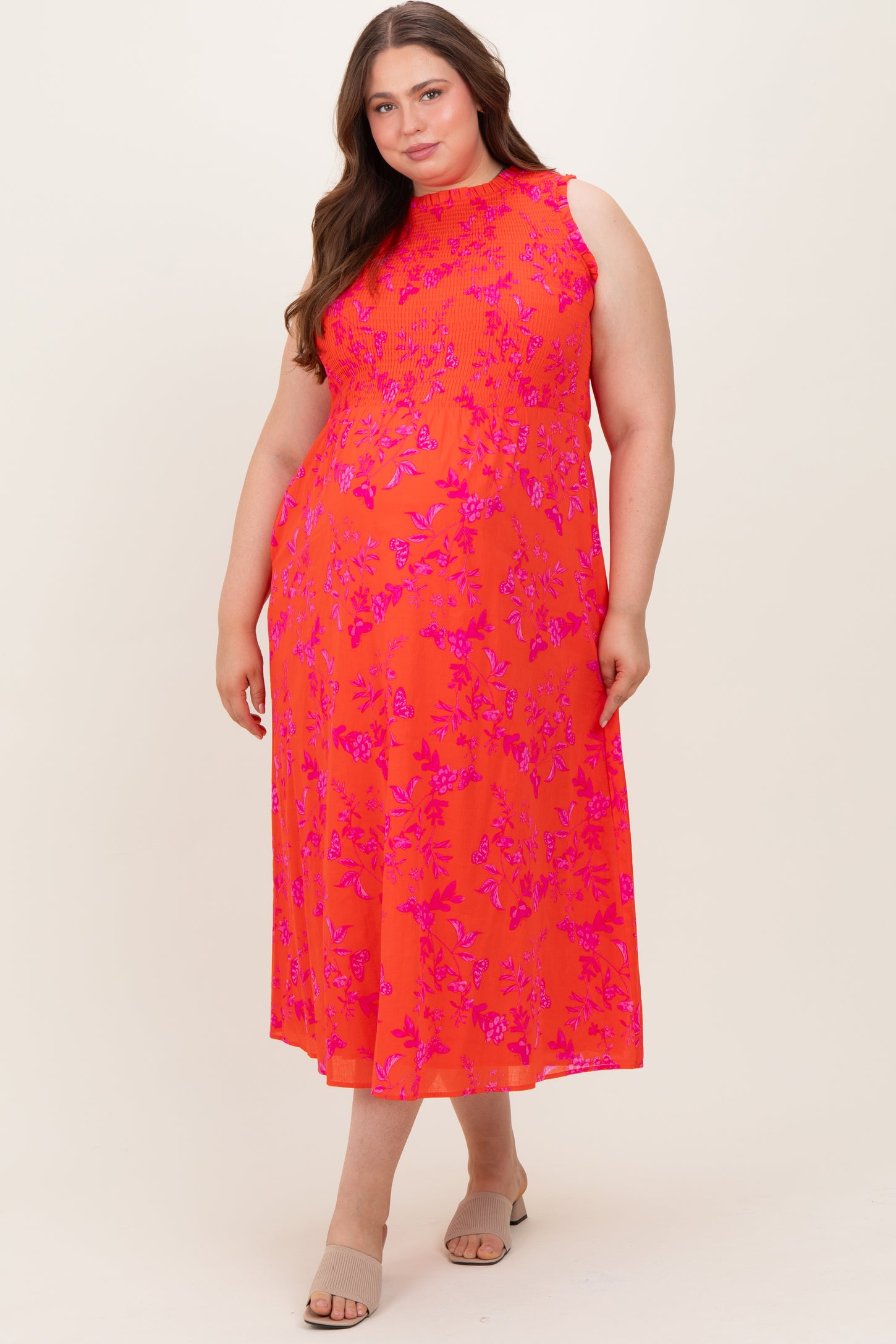 woman wearing a bright pink floral maxi maternity dress with sleeveless design and a fitted bodice