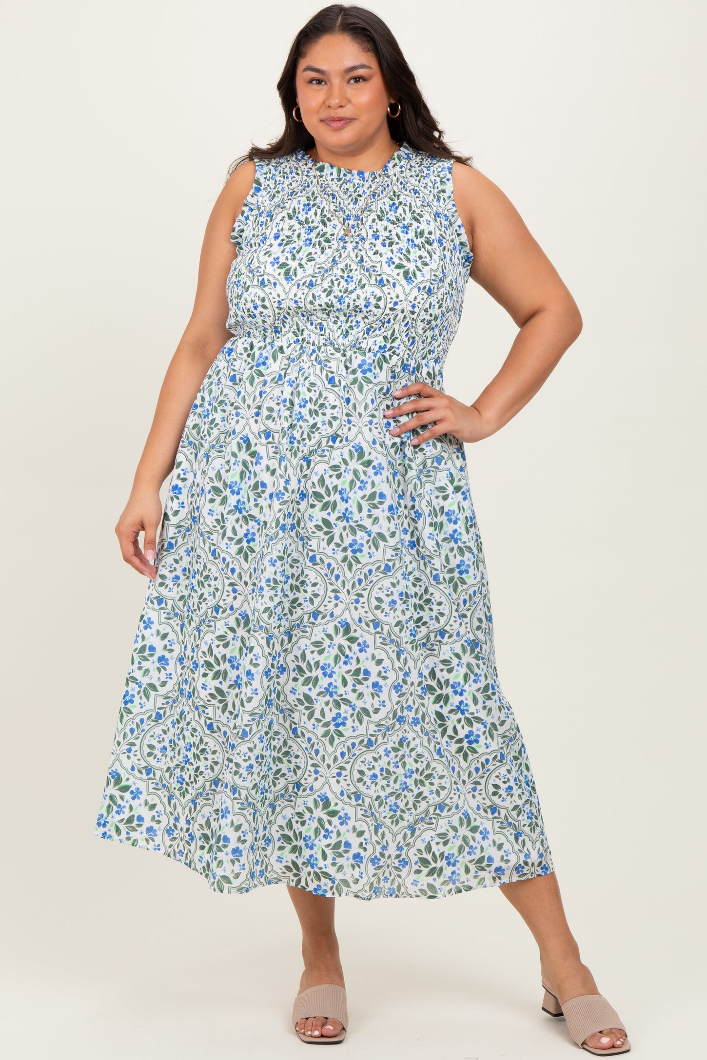 woman wearing a sleeveless plus-size maxi dress with a floral print in blue and green shades