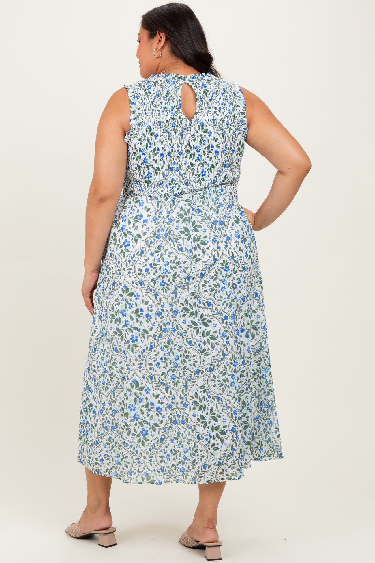 woman wearing a sleeveless blue and white floral maxi dress with a keyhole back and elastic waist, seen from the back
