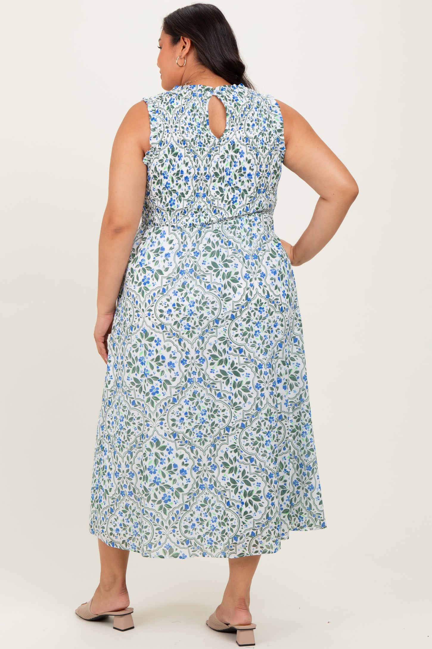 woman wearing a sleeveless blue and white floral maxi dress with a keyhole back and elastic waist, seen from the back