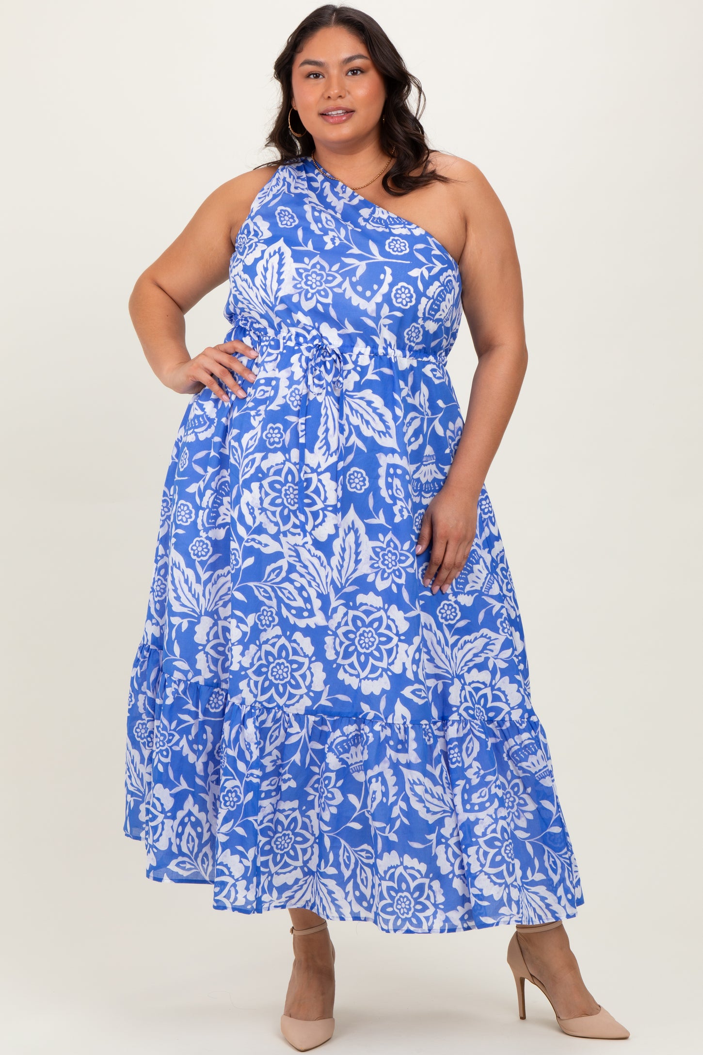 woman wearing a blue floral plus size maxi dress with a one-shoulder design and tiered ruffles