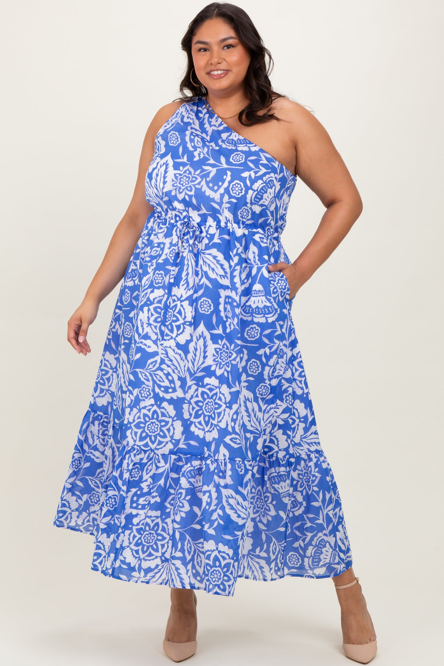 woman wearing a blue and white floral print plus size maxi dress with one shoulder and pockets