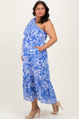 woman wearing a blue and white one-shoulder floral dress with pockets and a flowing skirt, standing sideways