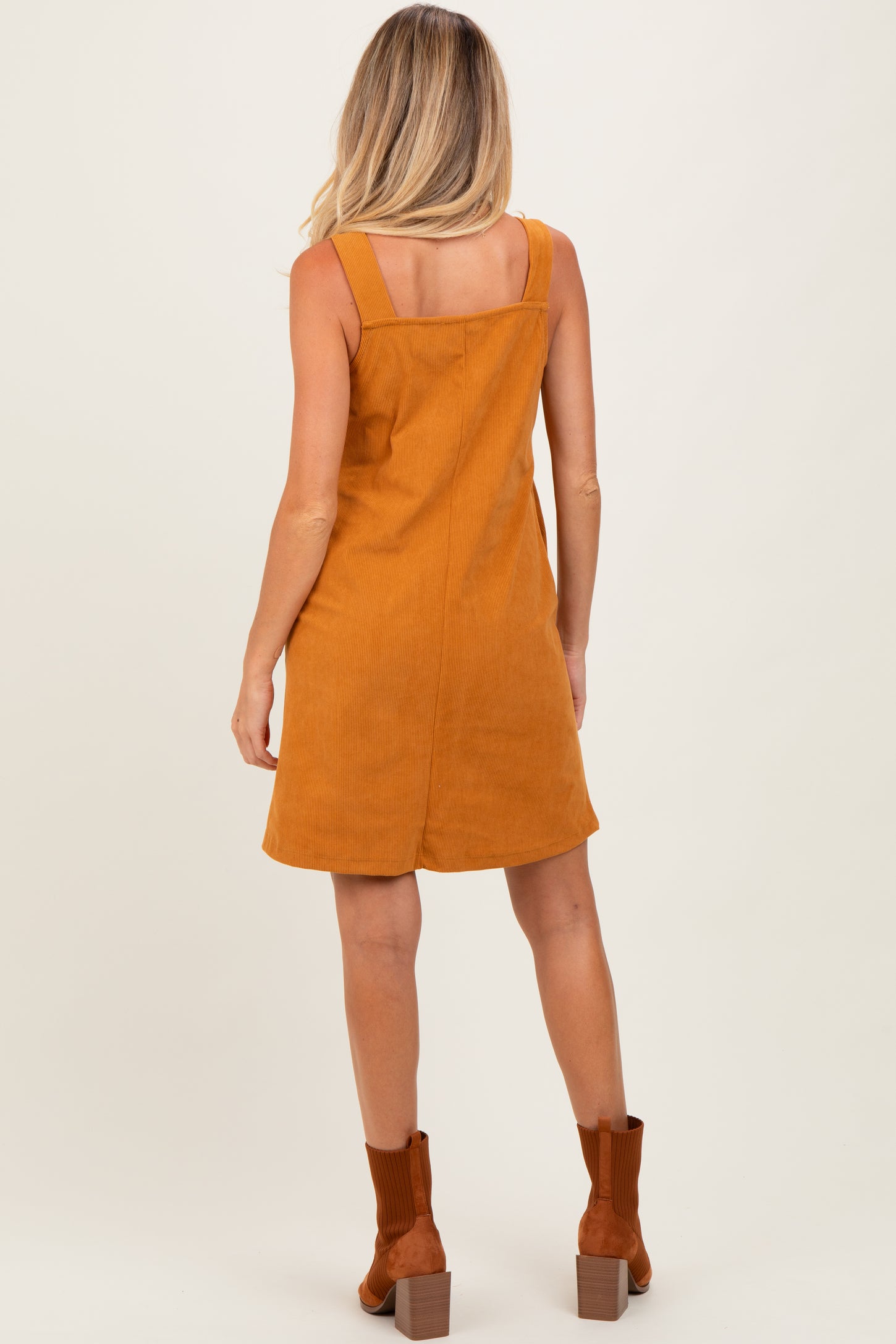 woman wearing a mustard corduroy maternity dress with a fitted bodice and flared skirt, viewed from the back