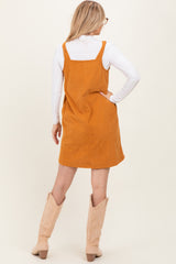 woman wearing a mustard yellow corduroy overall dress with a fitted bodice and a flared skirt, seen from the back