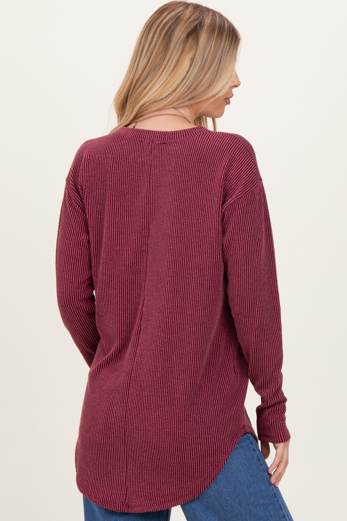 woman wearing a maroon long sleeve ribbed top with a relaxed fit and high-low hem