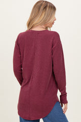 woman wearing a maroon long sleeve ribbed top with a relaxed fit and high-low hem