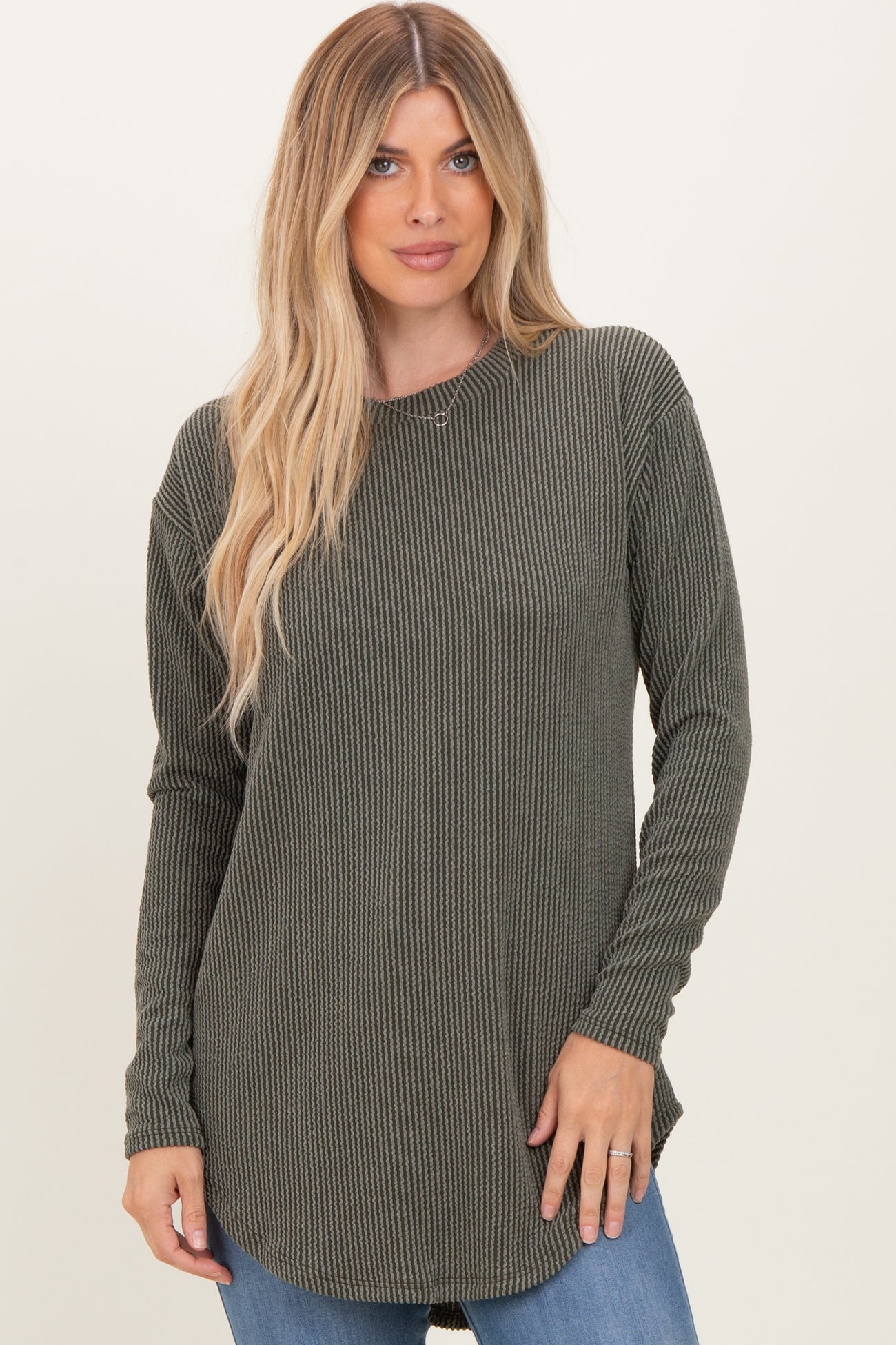 woman wearing an olive green long sleeve ribbed top with a round neckline and curved hemline