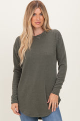 woman wearing an olive green long sleeve ribbed top with a round neckline and curved hemline