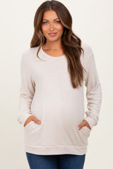 woman wearing a light beige maternity sweatshirt with side pockets and a visible baby bump