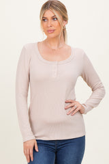 woman wearing a beige long sleeve henley top with button details and a scoop neckline paired with blue jeans