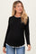 woman wearing a black maternity long sleeve top with a white ruffled hem and a visible baby bump
