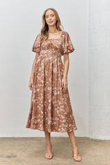 woman wearing a brown floral midi dress with puff sleeves and a smocked bodice