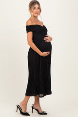 woman wearing a black off-shoulder maternity dress with pleated detail and holding her baby bump