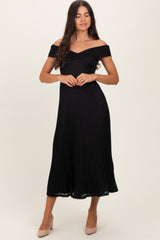 woman wearing a black off-the-shoulder pleated midi dress with a fitted bodice and flared skirt