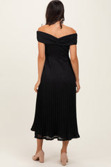 woman wearing a black off-the-shoulder pleated midi dress, showing the back view and styled with light-colored heels