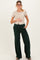 woman wearing a beige short sleeve top and green maternity loungewear pants with a visible baby bump