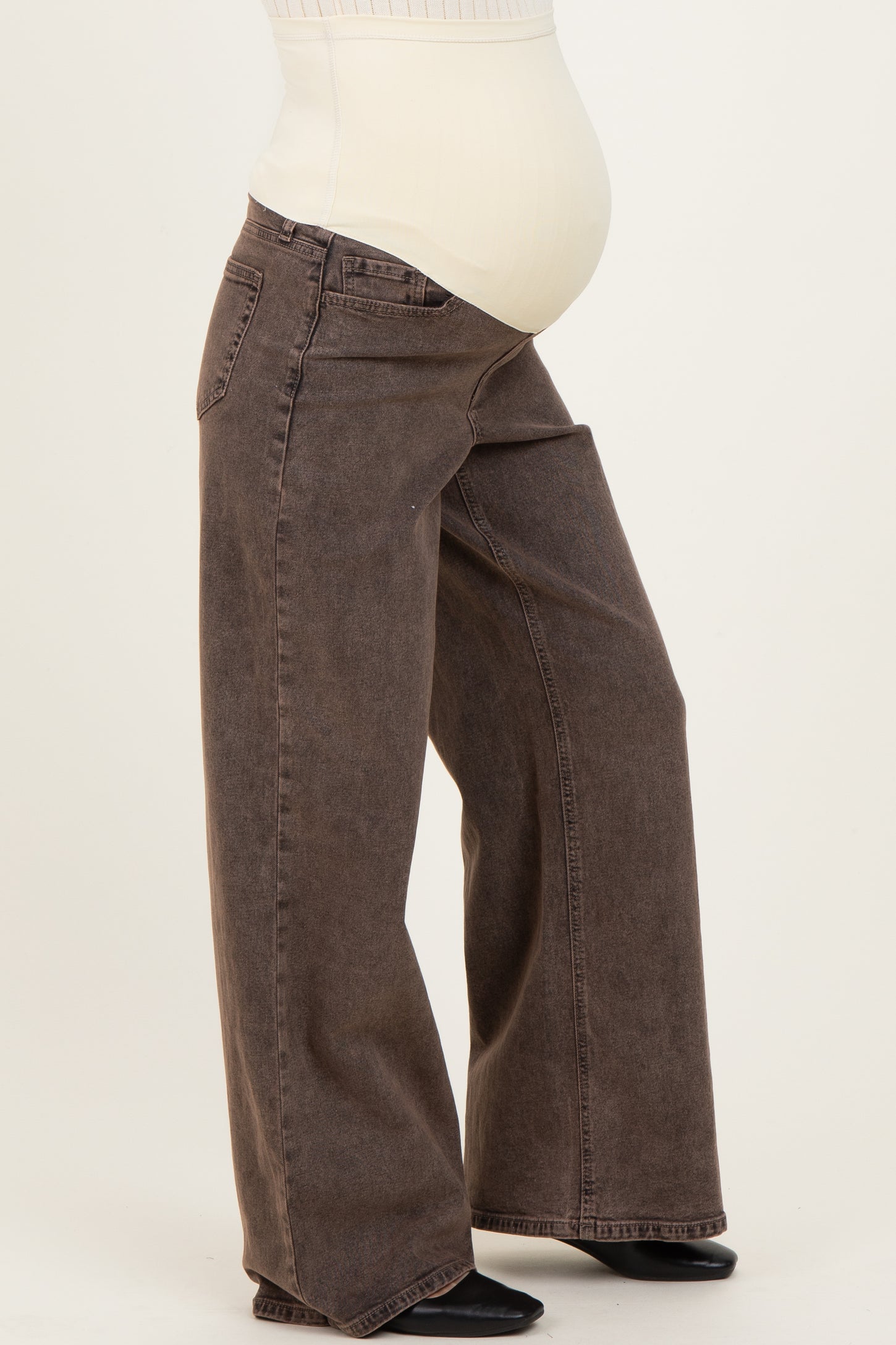 woman wearing a pair of brown wide-leg maternity jeans with a visible baby bump