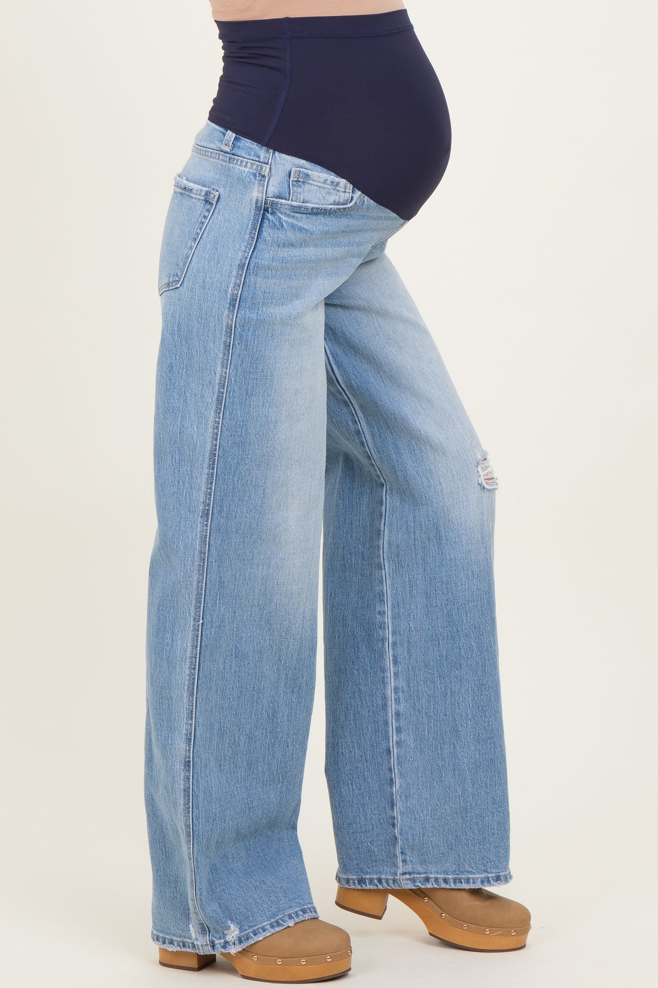 woman wearing light blue wide-leg maternity jeans with a navy blue panel and visible baby bump