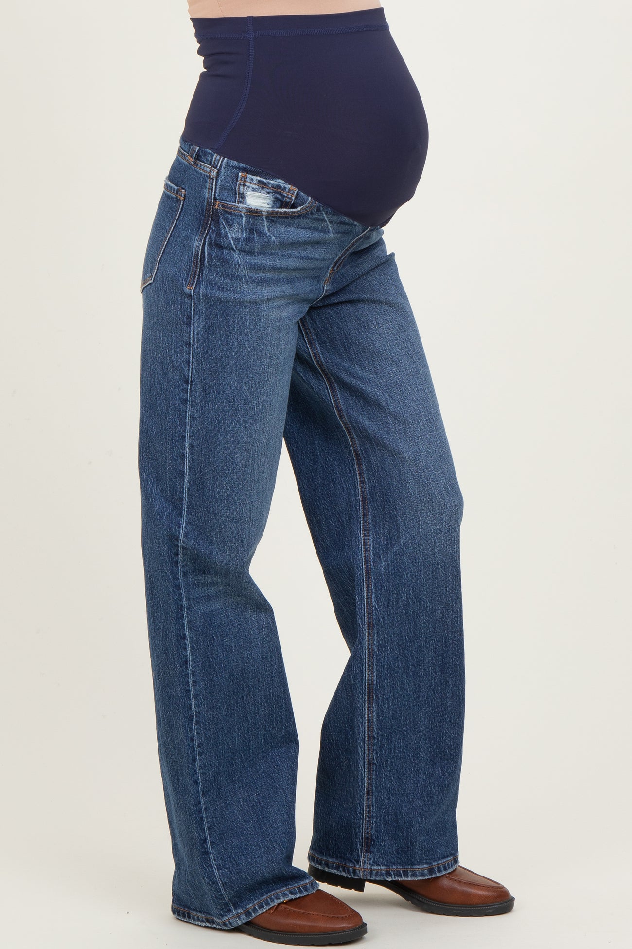 woman wearing a pair of dark blue maternity jeans with a smooth underbelly support band and flared leg style