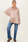 woman wearing a beige long sleeve maternity shirt with a relaxed fit and jeans, holding her baby bump