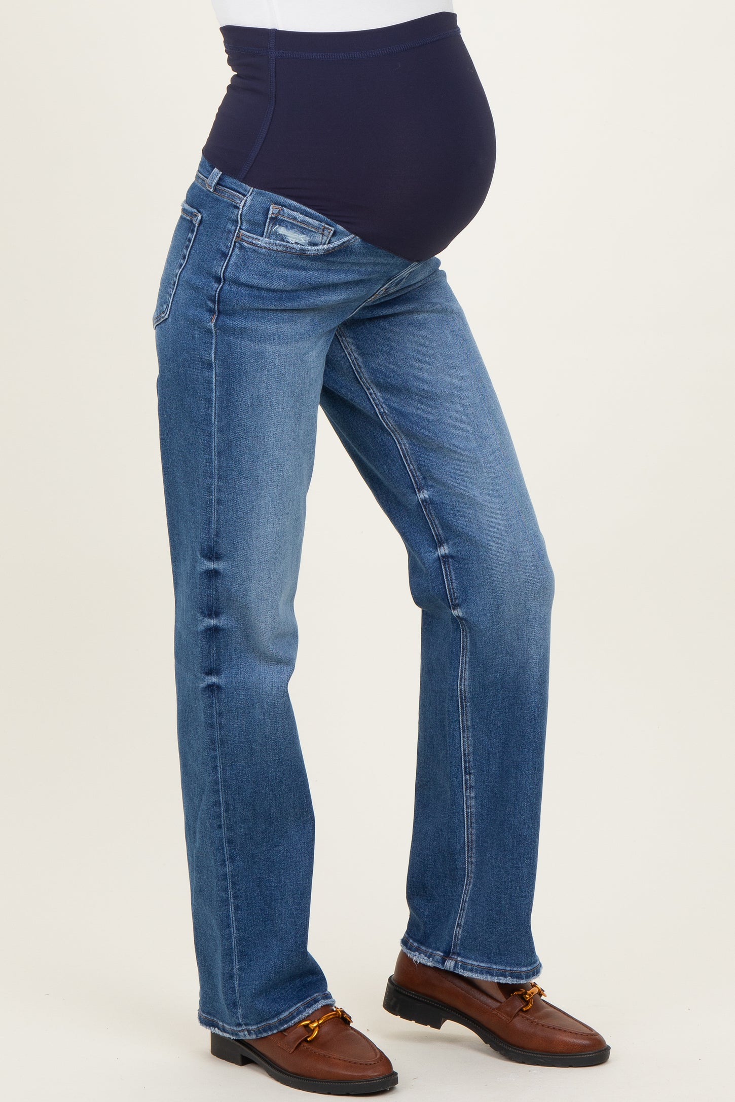 woman wearing blue maternity jeans with a black waistband and a visible baby bump