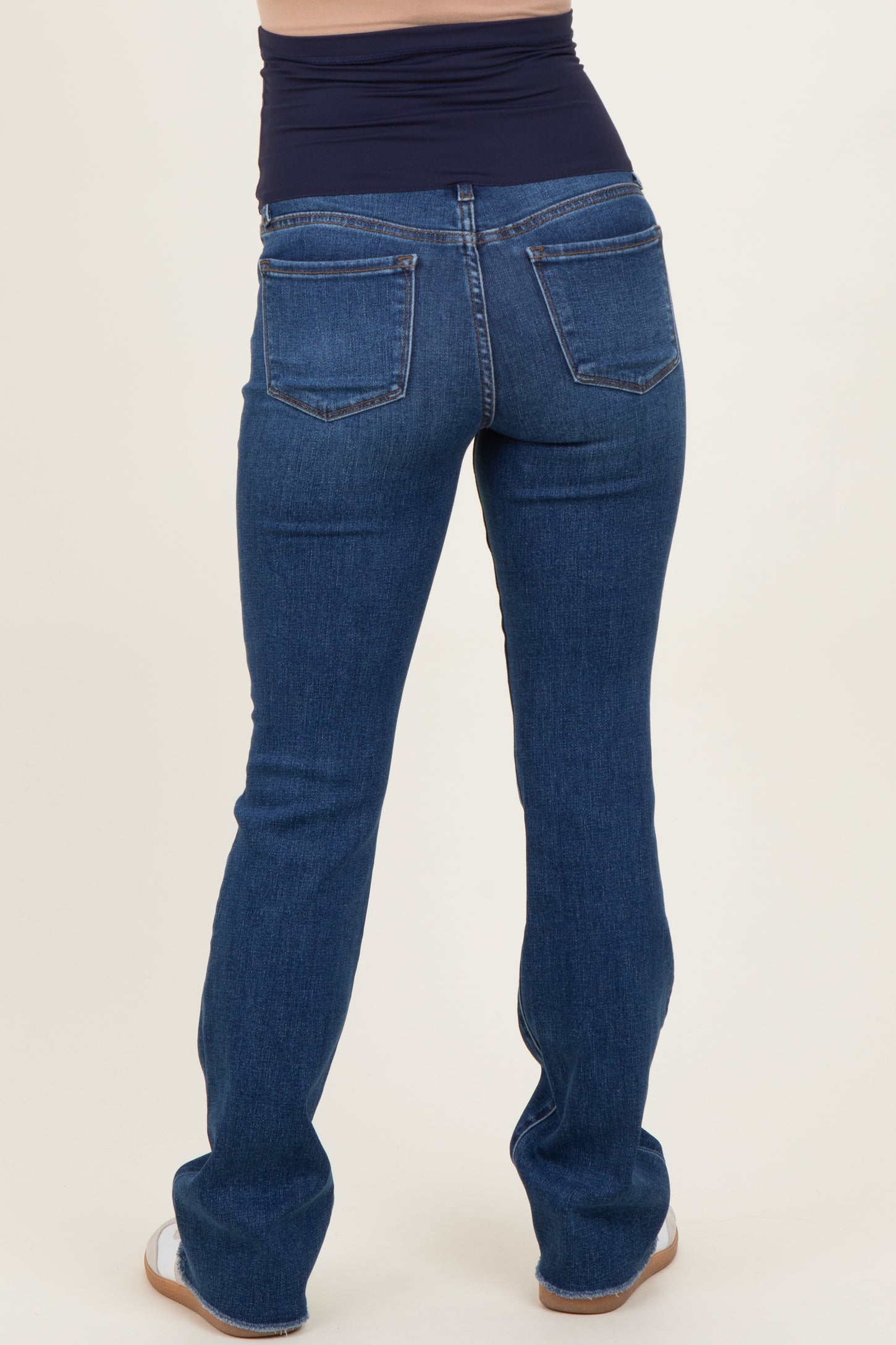 woman wearing dark blue maternity jeans with a low-rise waistband, showing the back view and a fitted style