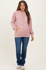 woman wearing a pink ribbed maternity hoodie with front pockets and jeans