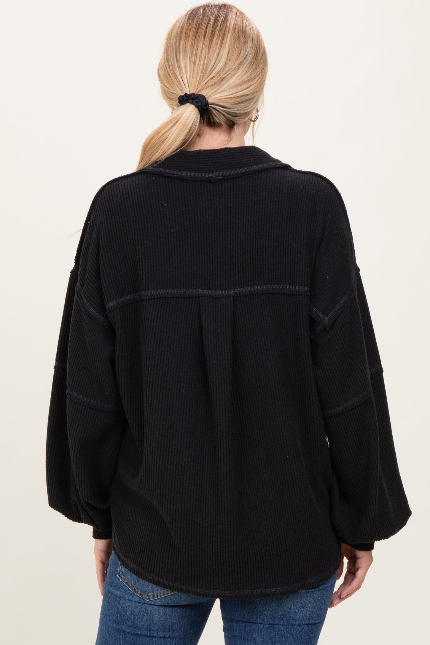 woman wearing a black ribbed oversized sweater with balloon sleeves, seen from the back