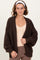 woman wearing a dark brown chunky knit cardigan over a beige top with ribbed sleeves and a relaxed fit