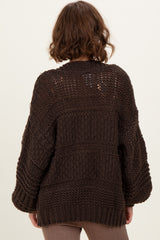 woman wearing a chunky dark brown knit sweater with oversized sleeves, viewed from the back