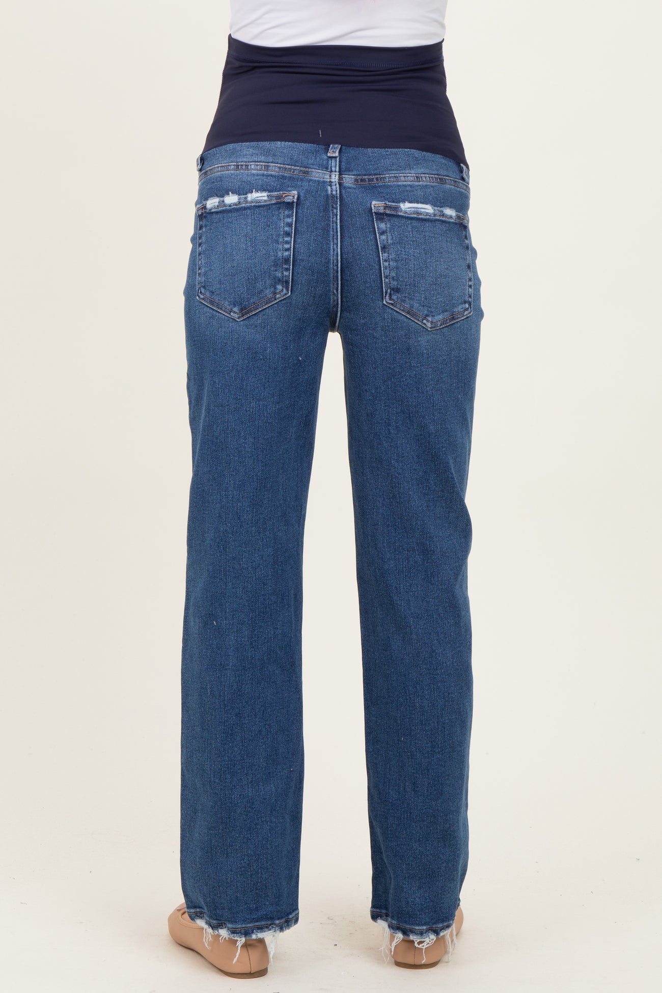 woman wearing a pair of distressed blue maternity jeans with a supportive belly band, viewed from the back