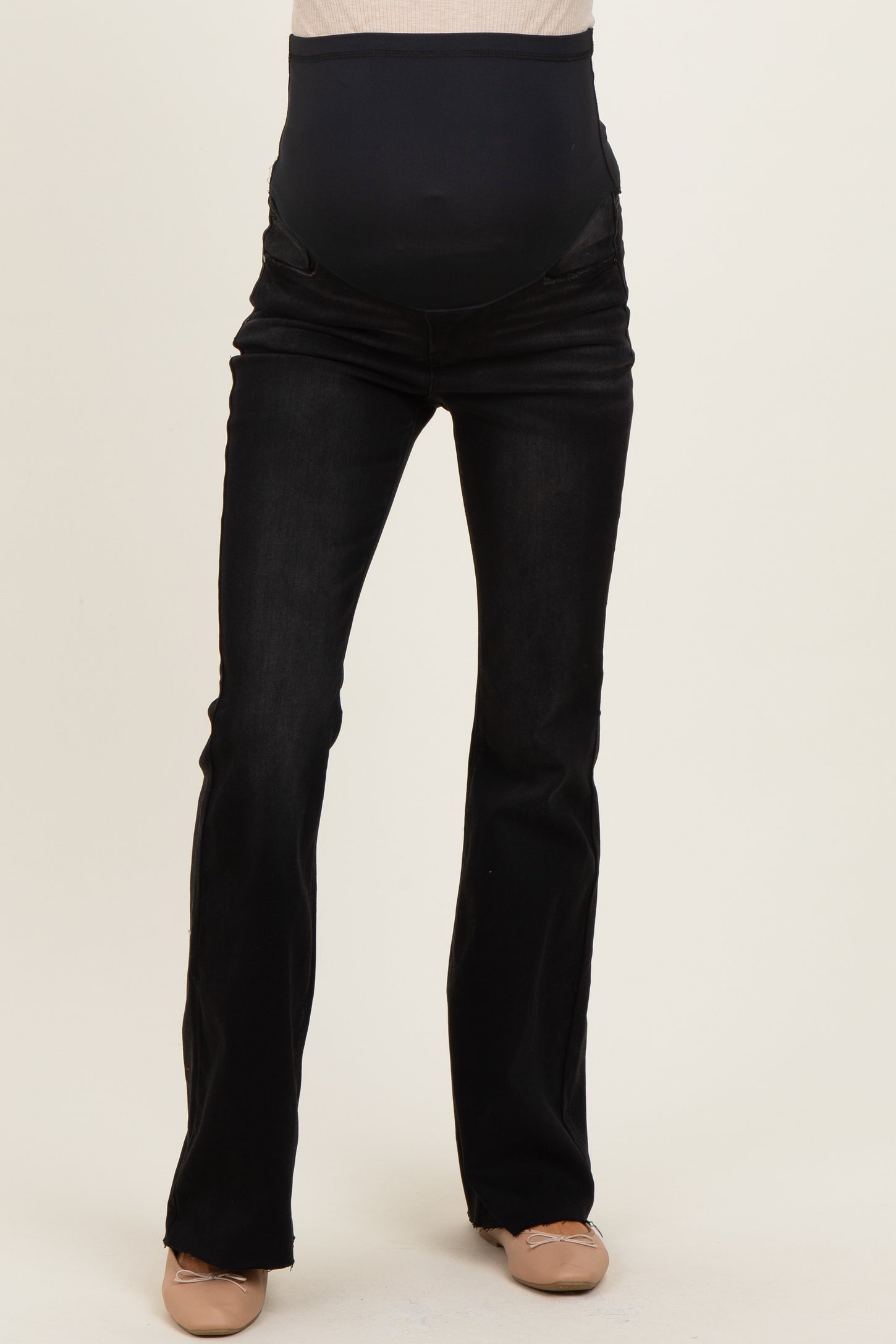 woman wearing black maternity jeans with a high waistband and a slight bootcut style, showing her baby bump