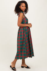 woman wearing a green plaid midi dress with tie shoulder straps and a scalloped hem