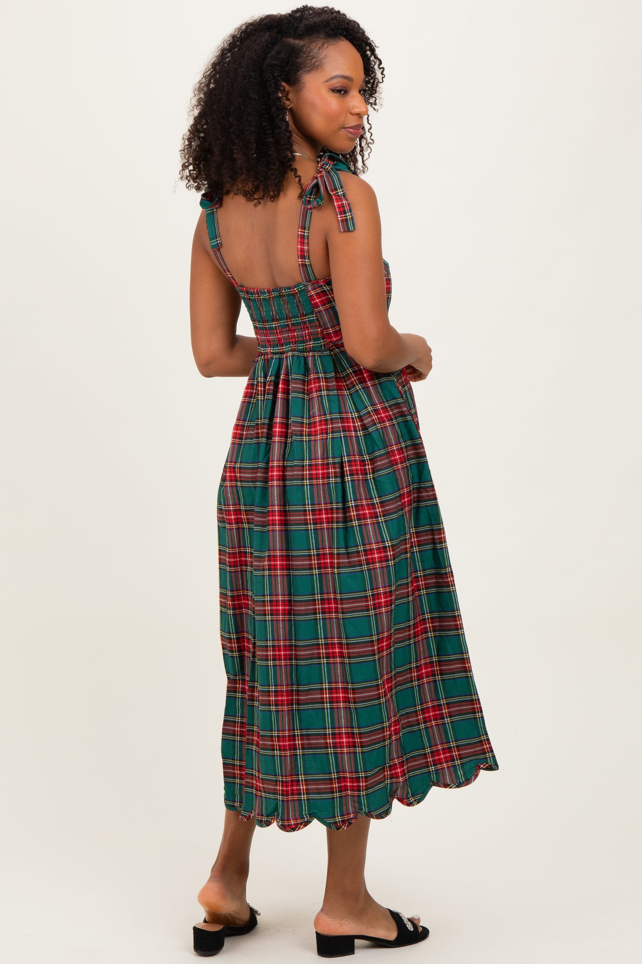 woman wearing a green plaid midi dress with a smocked back and halter straps, shown from the back
